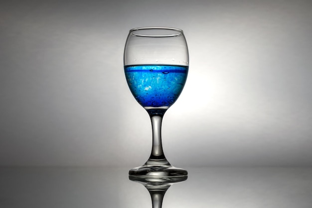 Verre à vin isolé sur fond gris avec un petit reflet en bas