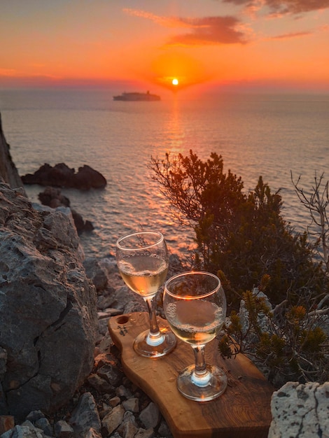 Verre de vin mer rendez-vous romantique au coucher du soleil de la falaise en arrière-plan