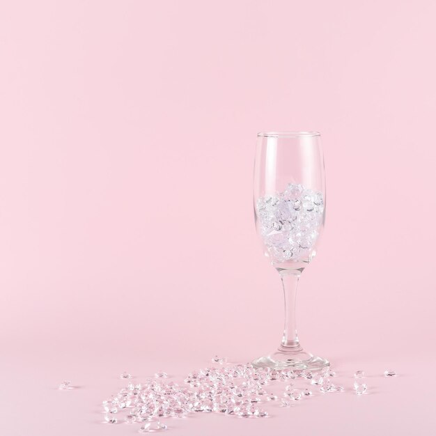 Verre à vin plein de diamants sur fond rose Concept de fête minimal créatif