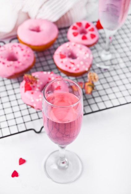 Verre de vin rose ou champagne et beignets roses sur la grille de cuisson. Concept de la Saint-Valentin.