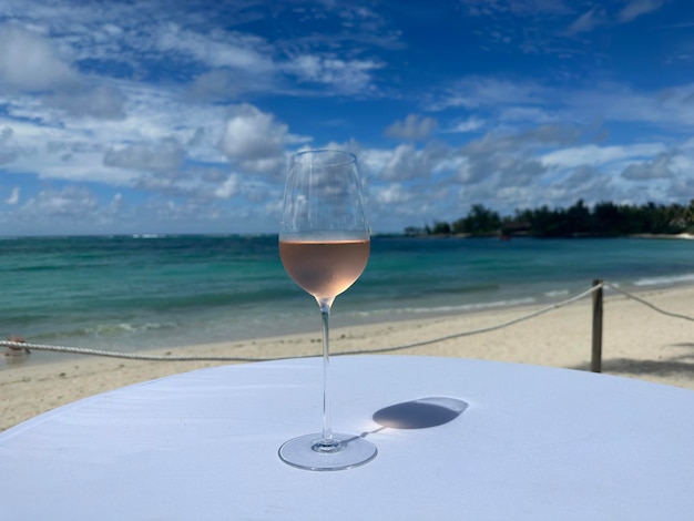 Verre de vin rosé sur la plage sur fond de mer ou d'océan