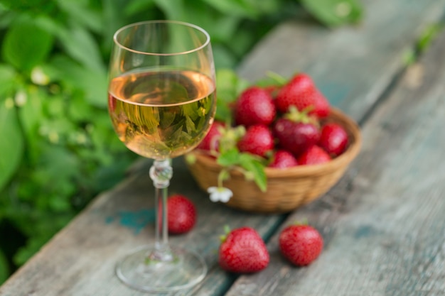 Un verre de vin rosé servi avec des fraises fraîches sur bois