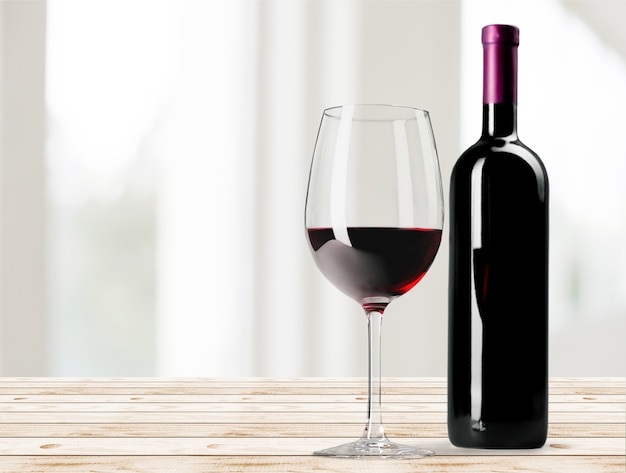 Verre à vin rouge sur un bureau en bois au fond du mur