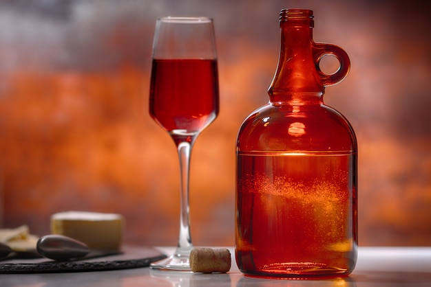 Verre de vin rouge, carafe et plateau de fromages sur un comptoir de bar ou de taverne