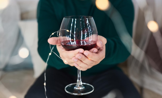 Verre de vin rouge dans les mains de l'homme et lumières bokeh dégustation de vin personnes alcool et boissons à la maison