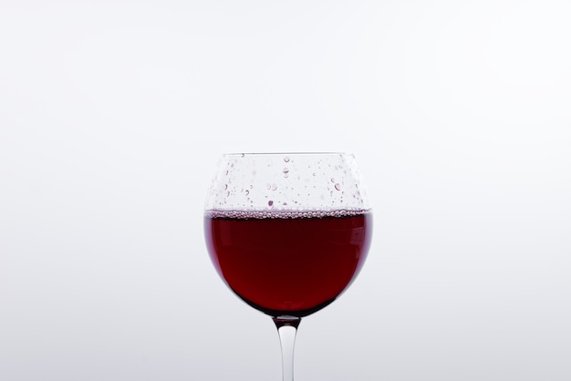 Un verre de vin rouge devant un mur blanc