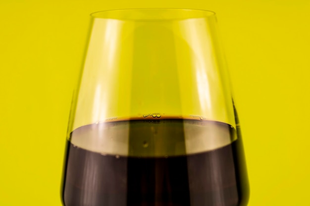 Un verre de vin rouge gros plan sur fond jaune