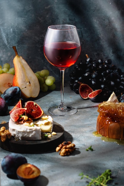 Verre de vin rouge avec raisin, figues, miel, poires et camembert