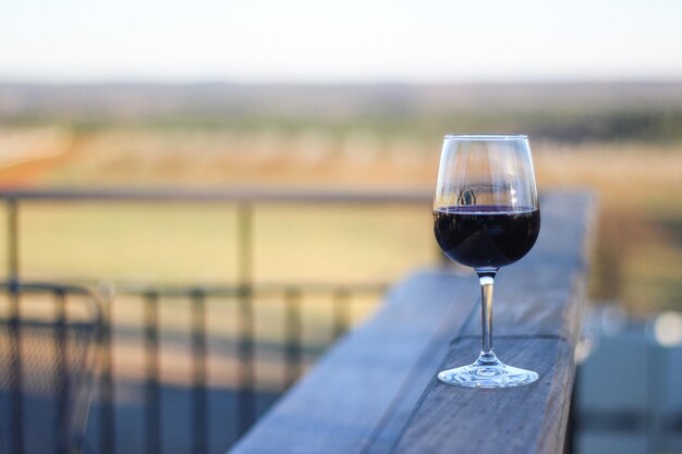 Un verre de vin sur une table en bois avec vue sur le vignoble en arrière-plan.