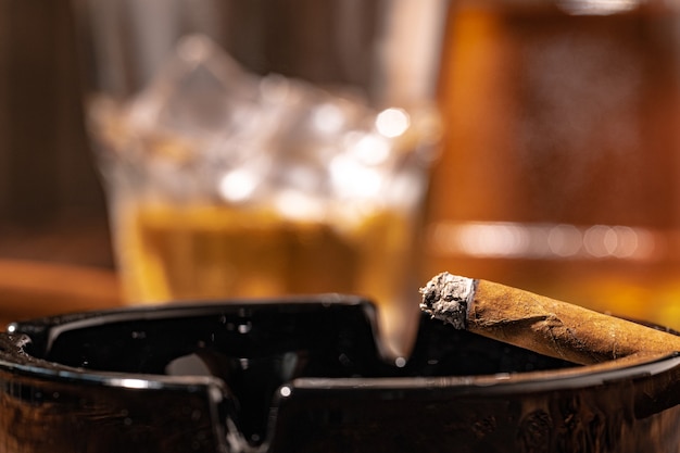 Verre de whisky et cigare allumé dans un cendrier