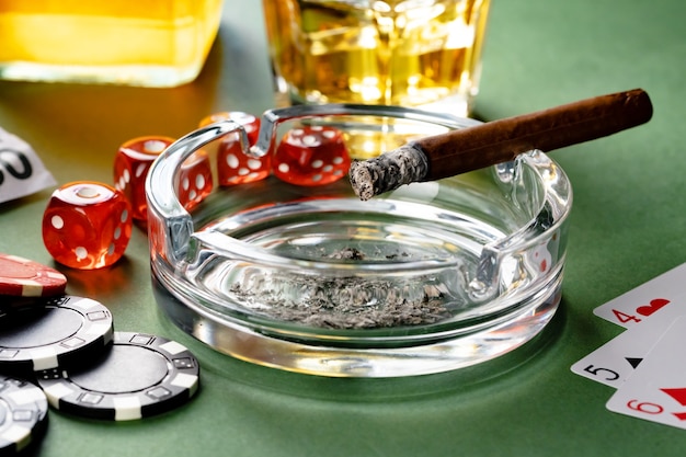 Verre de whisky cigare cartes à jouer et chips sur surface verte