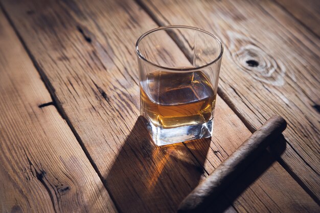 Verre de whisky et de cigare sur le fond en bois