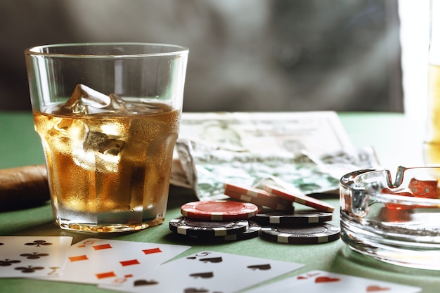 Verre de whisky cigare à jouer aux cartes et jetons sur vert