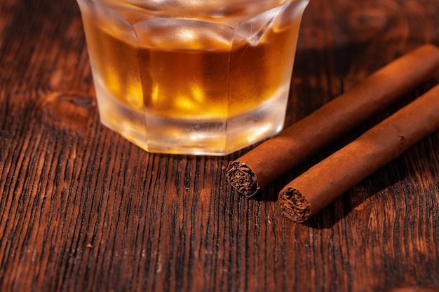 Un verre de whisky et de cigare sur une table en bois