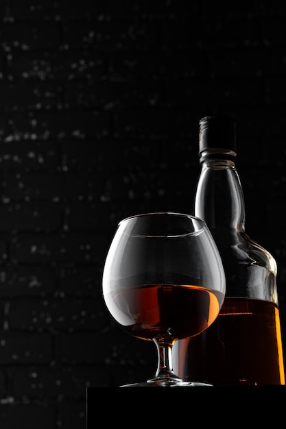 Verre de whisky contre le mur grunge noir foncé