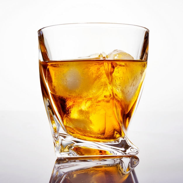 Verre de whisky écossais avec de la glace sur un fond blanc