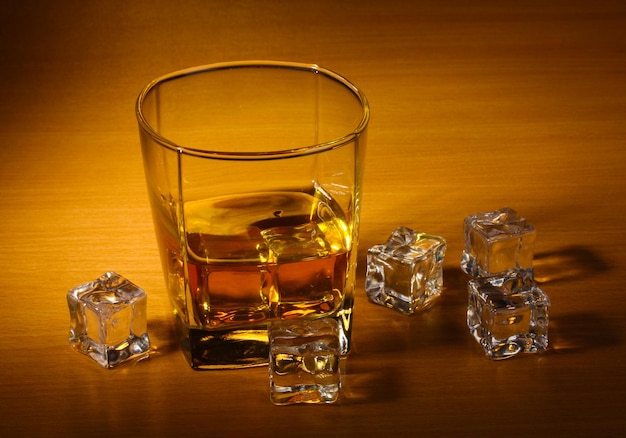 Verre de whisky écossais et glace sur table en bois