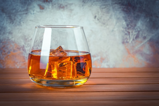 Photo verre de whisky avec de la glace. nature morte. brandy, bourbon sur une table en bois marron. boisson alcoolisée forte. rhum, scotch. copiez l'espace pour le texte.