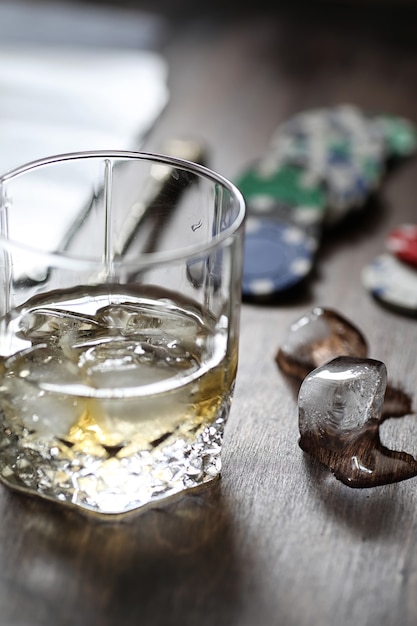 Un verre de whisky et de glace sur la table de jeu avec des jetons et des cartes