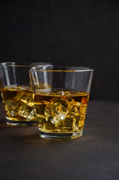 Verre de whisky avec des glaçons sur le vieux fond rouillé.