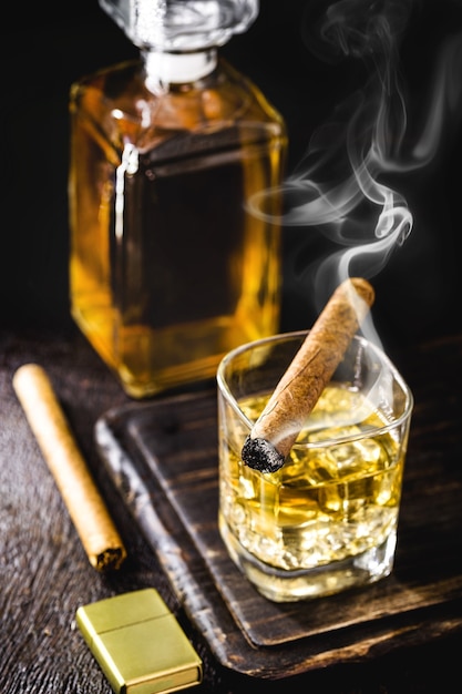 Verre à whisky et pinces à glace avec cigare sur table en bois