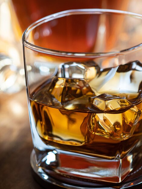 Verre de whisky sur les rochers sur un bar en bois avec des bouteilles en arrière-plan