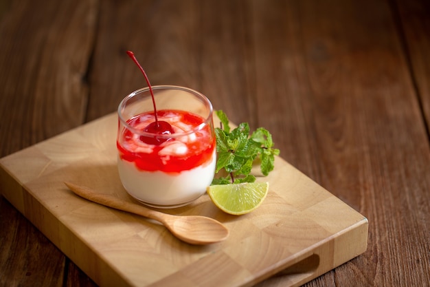 Verre de yogourt cerise sur une table en bois brun.