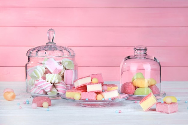 Verrerie avec des bonbons colorés sur fond de bois rose