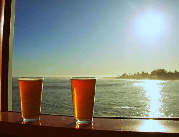 Des verres de bière sur le seuil de la fenêtre contre la mer