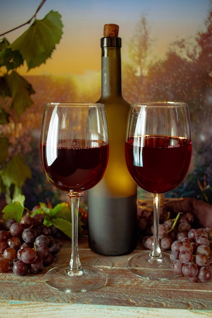 Verres et une bouteille avec des grappes de vin rouge de raisin coucher de soleil atmosphère romantique