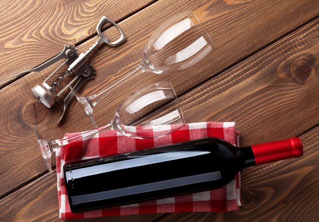 Verres de bouteille de vin rouge et tire-bouchon sur table en bois