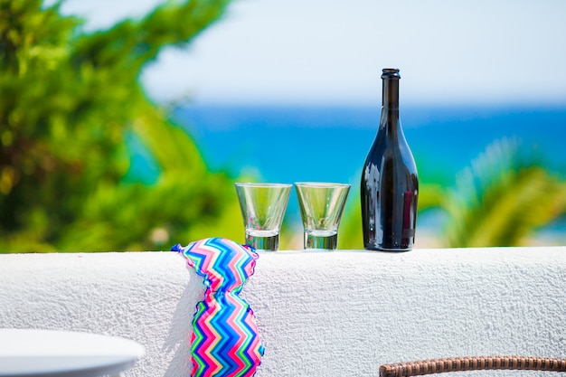 Verres, bouteille de vin savoureux et maillot de bain