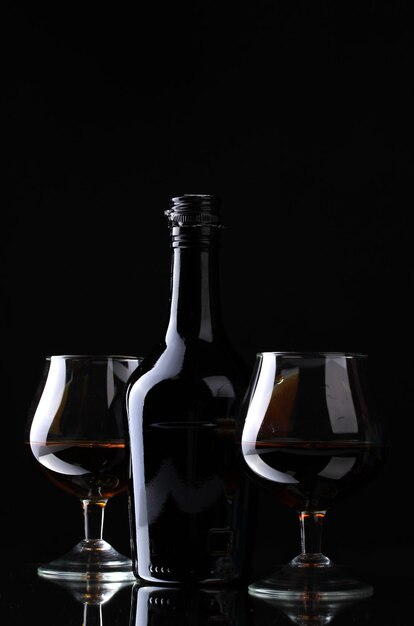 Verres de brandy et bouteille sur fond noir