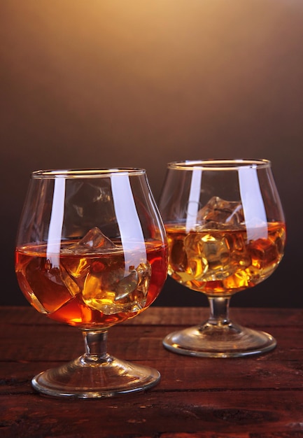 Verres à brandy avec de la glace sur une table en bois sur fond marron