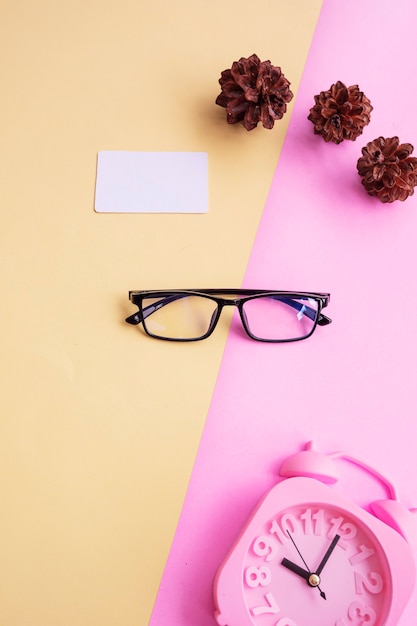 Verres Carrés Sur Fond Rose Et Jaune Avec Accessoires Supplémentaires, Réveil Et Fleurs De Pin. Style D'été Minimal