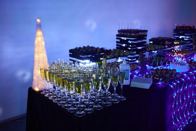 Verres de champagne magnifiquement brillants sur la table dans le contexte d'une atmosphère festive avec éclairage au néon.