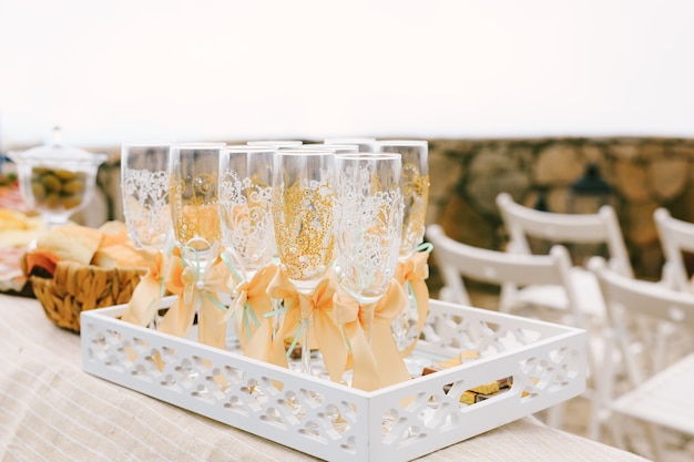 Verres à Champagne De Mariage Avec Un Motif Et Des Nœuds Beiges Sur Un Plateau Blanc Ajouré Sur La Table