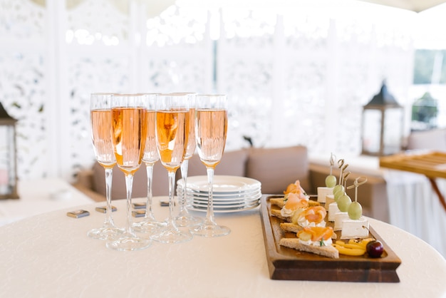 Verres de champagne rose sur la table du buffet à côté d'une assiette d'apéritifs