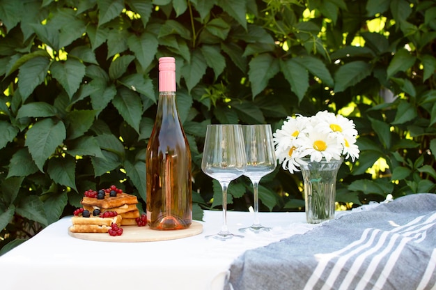 Verres de champagne sur table avec vue sur la nature verdoyante Maquette de bouteille de vin avec une étiquette vide sur la table Concept de vacances d'été à la plage et passe-temps romantique avec une boisson pétillante alcoolisée