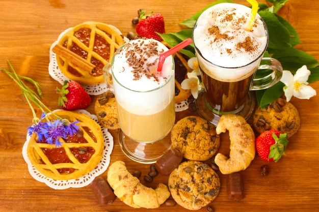 Verres de cocktail de café sur table en bois avec des fleurs et des douces