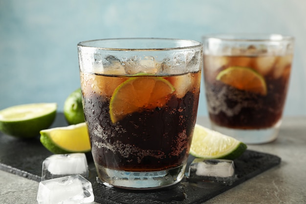 Verres avec cola froid et agrumes sur table grise, espace pour le texte