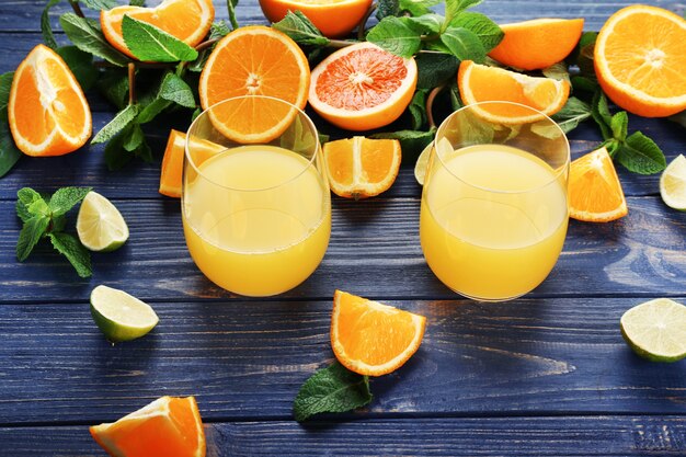 Verres avec un délicieux jus d'orange et d'agrumes sur table en bois