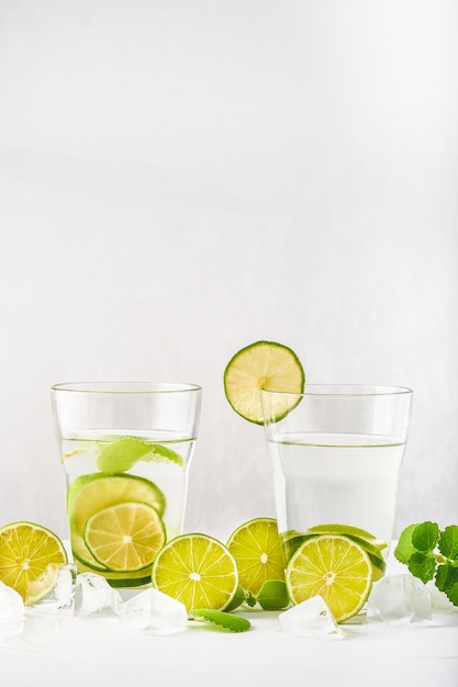 Verres avec eau, tranches de citron vert, menthe et glaçons