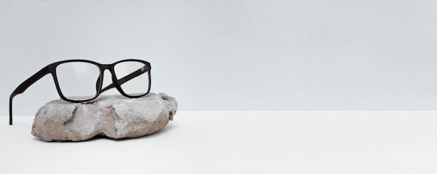 verres sur fond gris avec pierre. concept de vente de lunettes. Copiez l'espace pour le texte.