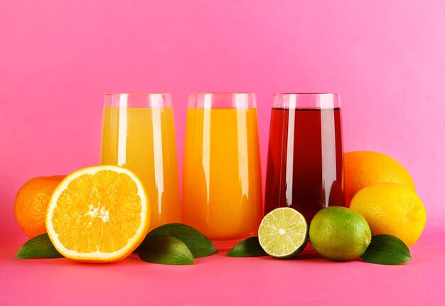 Verres de juise avec feuilles et fruits sur fond rose