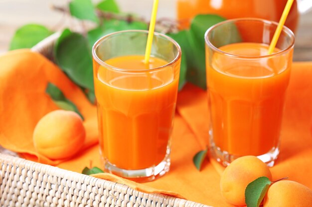 Verres de jus d'abricots dans le plateau en osier libre