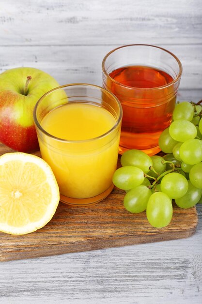 Des verres de jus avec des fruits frais sur une table en bois gris