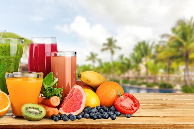 Verres de jus de fruits et légumes avec des fruits sur fond blanc