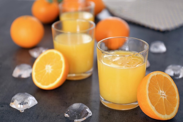 Verres avec jus d'orange frais et fruits sur table