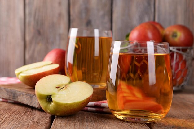 Verres de jus de pomme sur fond de bois